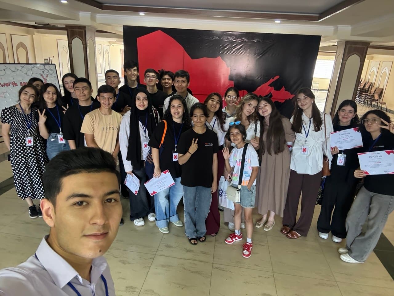 TEDxYouth tadbiri ishtirokchilari sertifikatlari bilan birga suratga tushmoqda